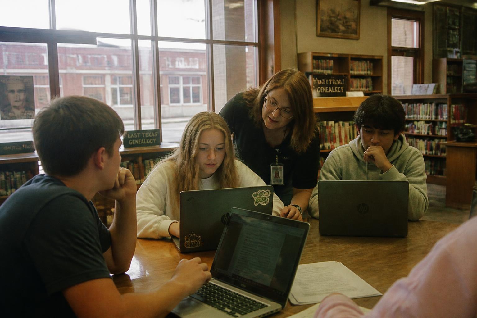 Students and a librarian working on laptops in a small-town East Texas library